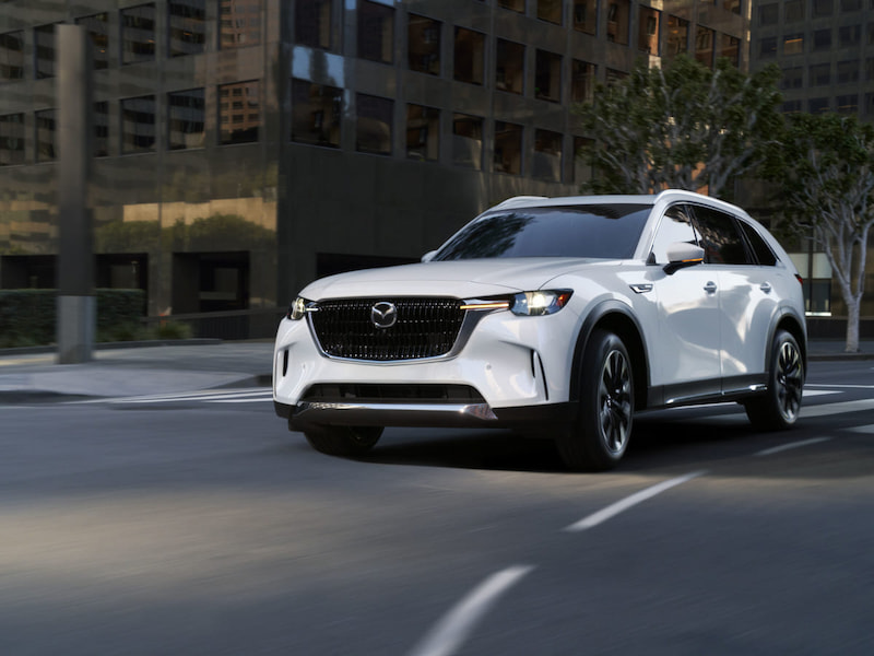2025 mazda cx-90 cresting the hill of a road