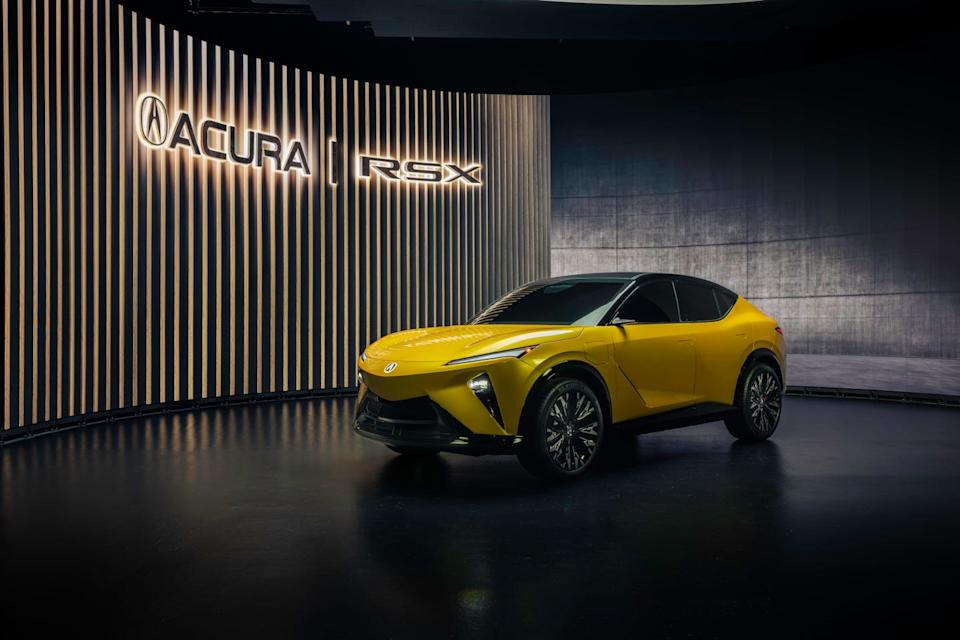 front three quarter view of yellow suv with black roof, vertical headlights, and closed grille on dark showroom floor.